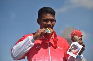 Atlet dayung putra Indonesia Marjuki menggigit medali emas ketika prosesi penyerahan medali setelah finish pertama final kano nomor C1 1000 meter putra SEA Games ke-28 di Teluk Marina, Singapura, Sabtu (6/6). Marjuki mempersembahkan medali emas pertama bagi Indonesia. ANTARA FOTO/Wahyu Putro A/Rei/nz/15.